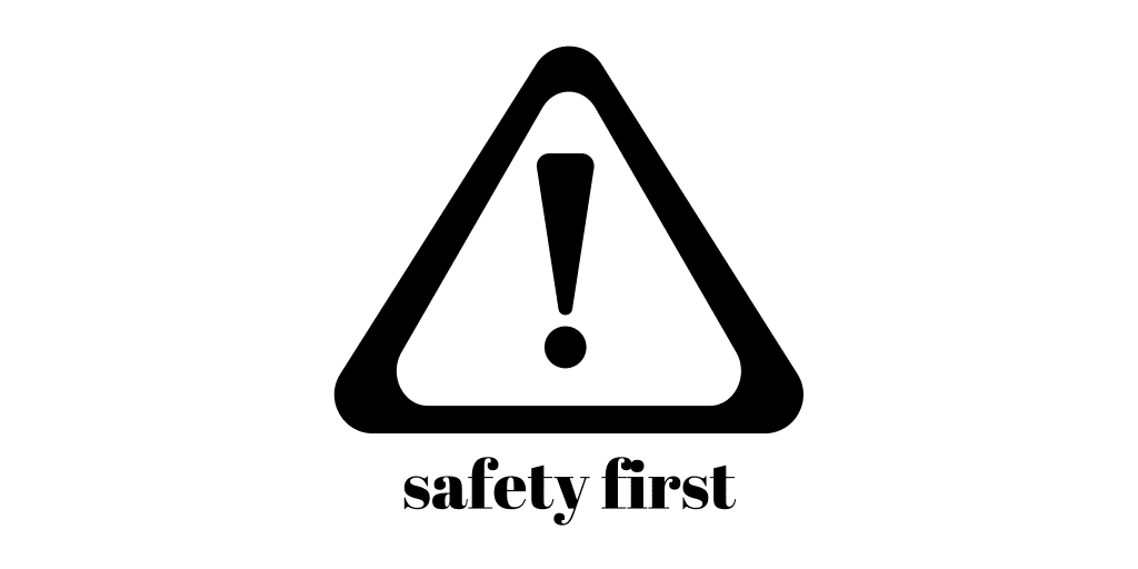 A black triangular warning sign with an exclamation mark inside, above the words safety first in bold, lowercase letters. The background is white.